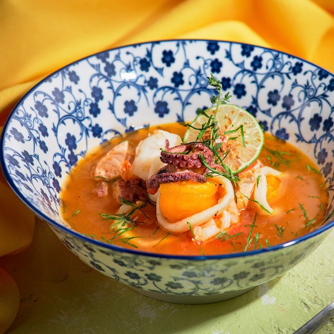 French Bouillabaisse fish soup with seafood, salmon fillet, shrimp, rich taste, tasty dinner. Side view, close-up, menu.