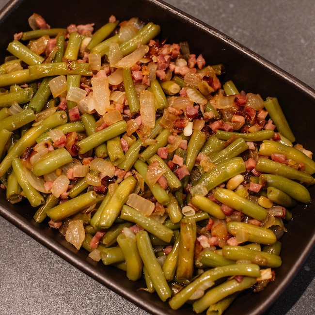 Green beans with ham. Plate of green beans cooked with serrano ham on a pyrex