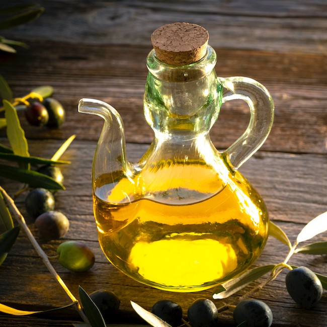 Olive oil bottles with olive tree branches leaves and olives on wooden rustic background at Mediterranean
