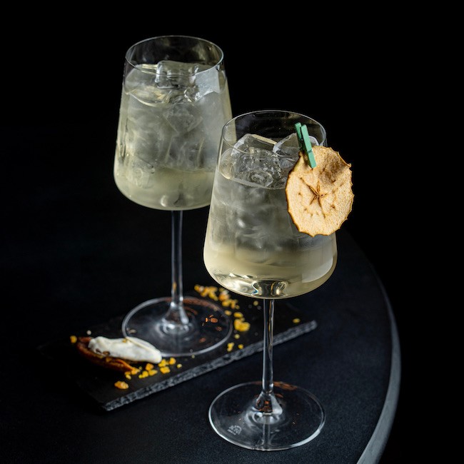 A pair of goblets with gin cocktails in a dark empty bar, side view