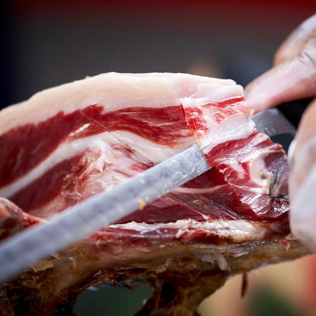 Man cutting a piece of iberian ham.