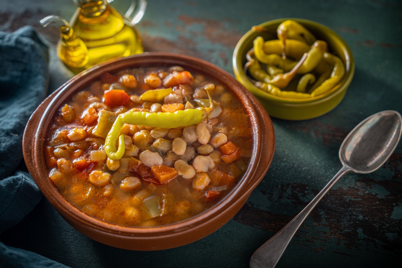 Pochas a la Navarra Spain white beans traditional stew with peppers and chili on a clay plate, Mediterranean food vegan plant based.