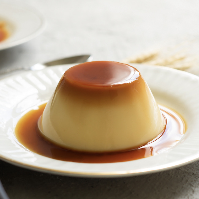Cream caramel pudding with caramel sauce in plate on white rustic table