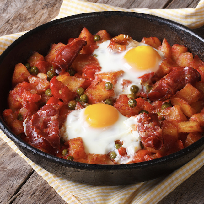 Spanish Food: eggs over Flemish, a pan closeup. horizontal
