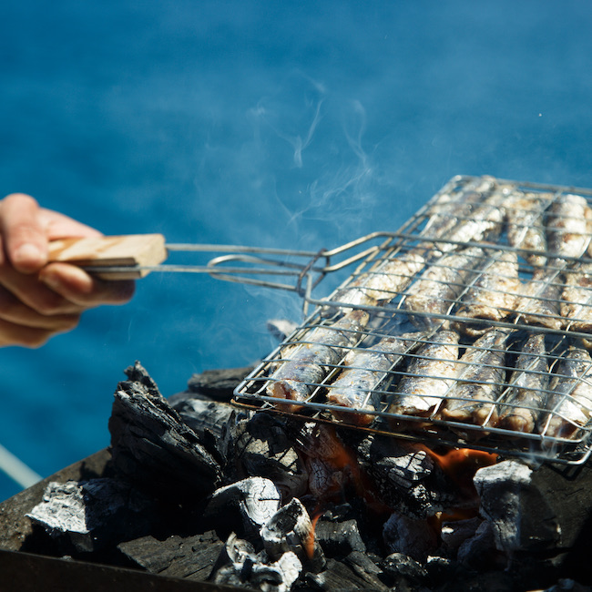 Fried sardines on an opened grill near the sea