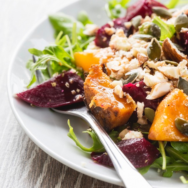 A beetroot and butternut salad on rocket topped with pumpkin seeds, nuts and a balsamic dressing