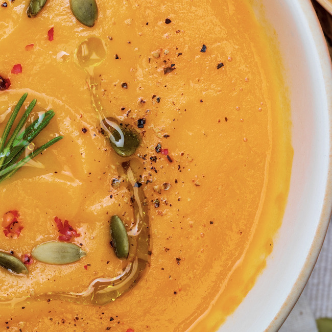 Close-up of a delicious pumpkin cream. Home and rustic appearance. Includes fresh pumpkin, seeds and rye bread. Aerial view.