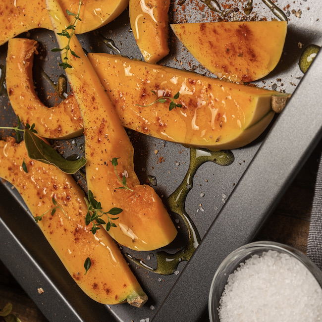 Many bright slices of pumpkin prepared for baking in the oven.