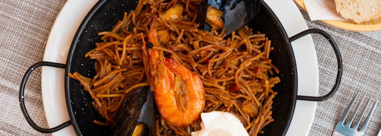 Delicious spanish dish seafood fideua, noodle paella served with aioli