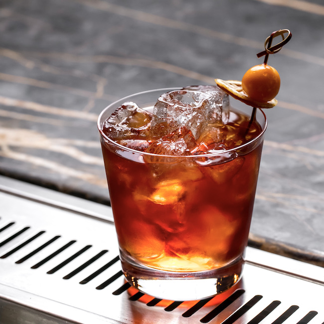 a cocktail glass with ice cubes garnished with dried lemon and fruit